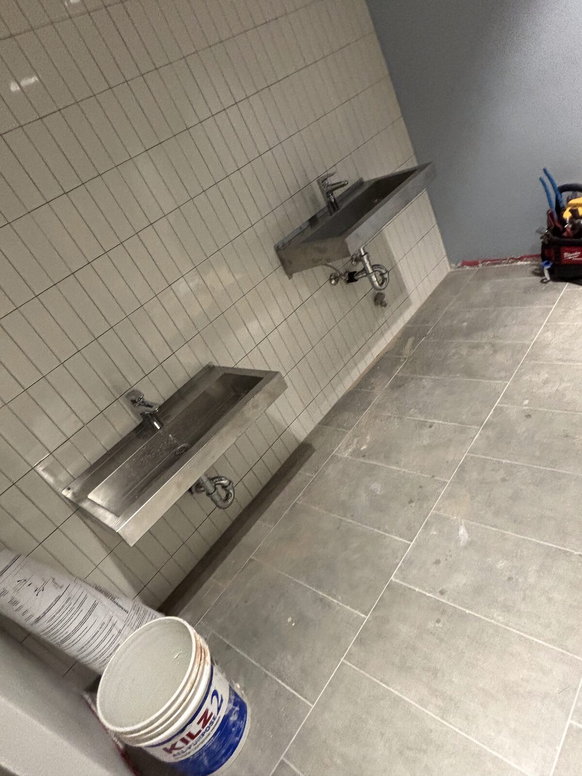 Commercial restroom with wall-mounted stainless sinks
